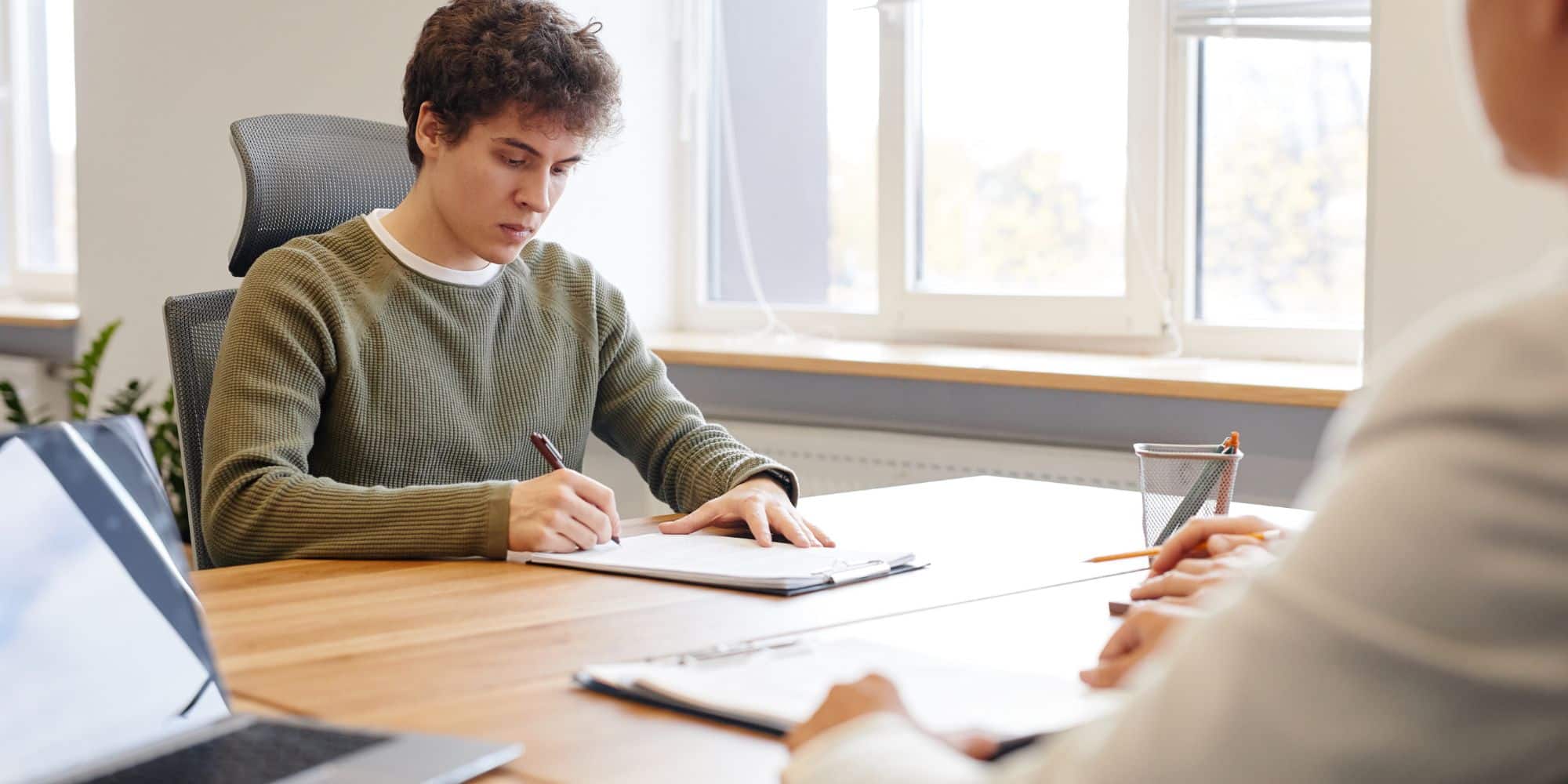Young employee in a hire for potential situation signs a contract