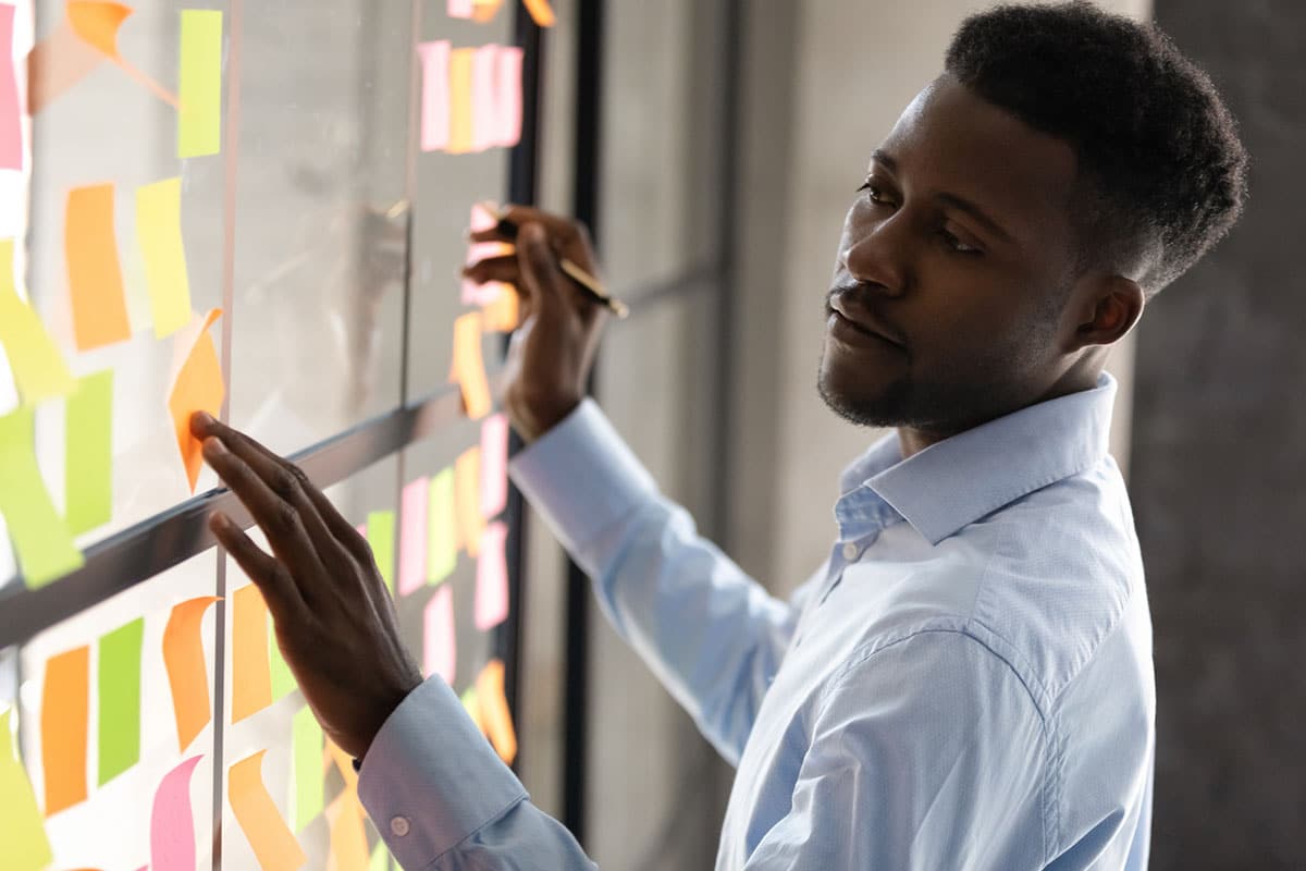 business man contemplates sticky notes on window showing how training can challenge employees
