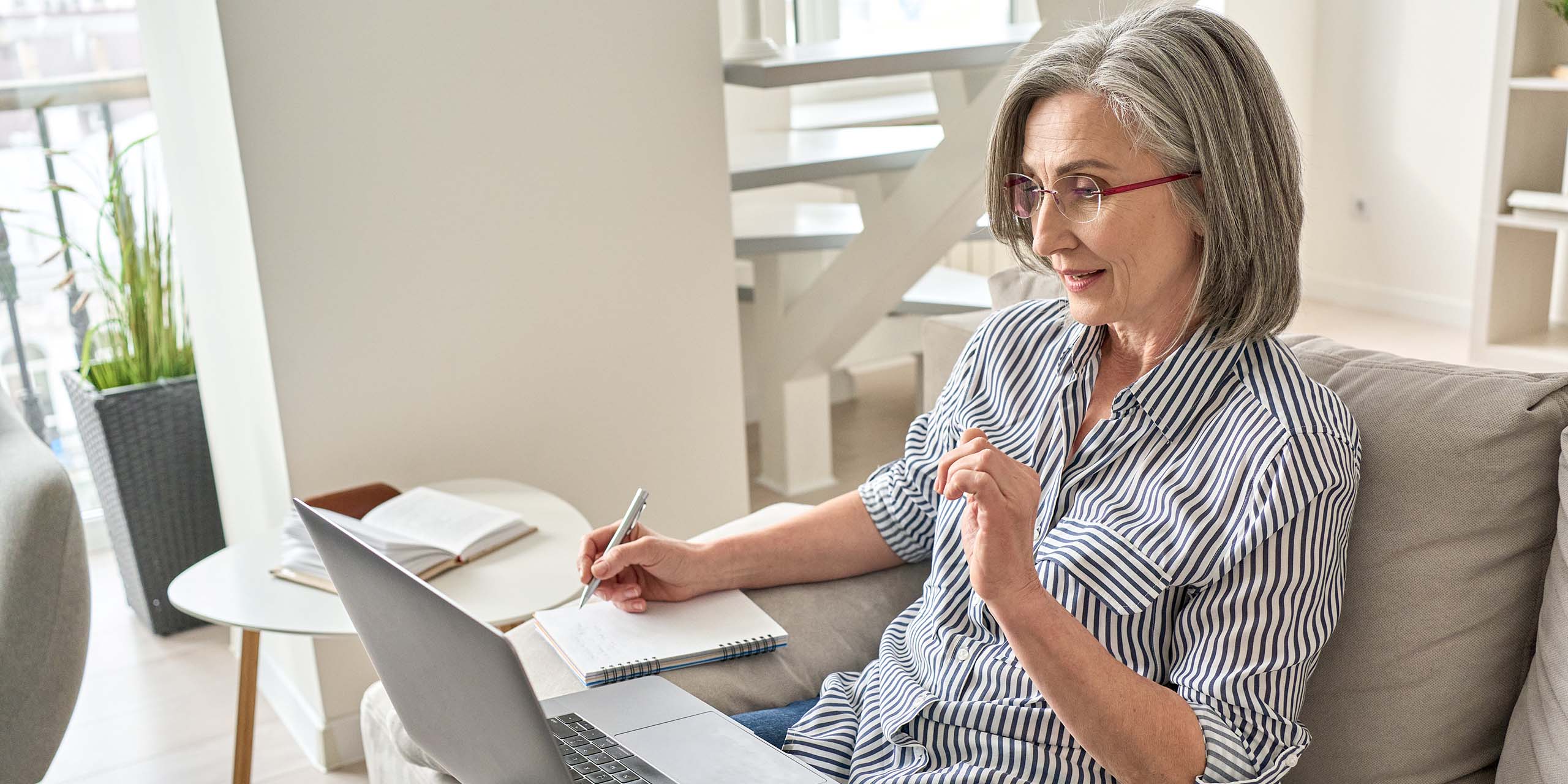 business woman goes through handwritten notes and compares them to digital content on laptop
