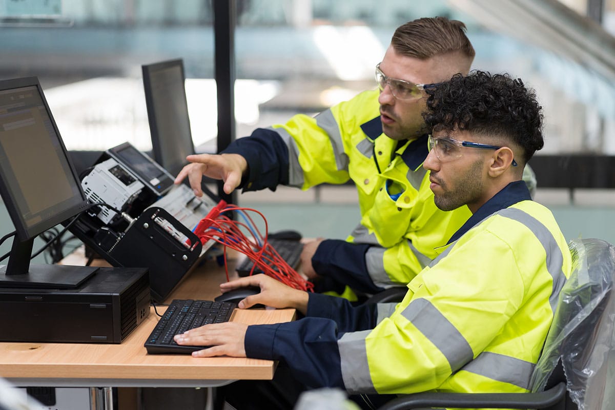 experienced employee shows apprentice how to use equipment