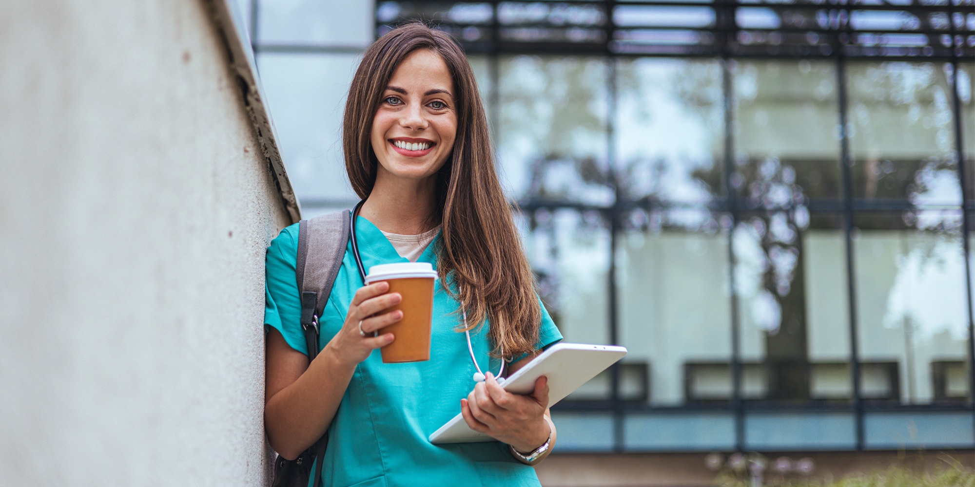 medical student accessing healthcare lms on tablet while drinking coffee and smiling at camera