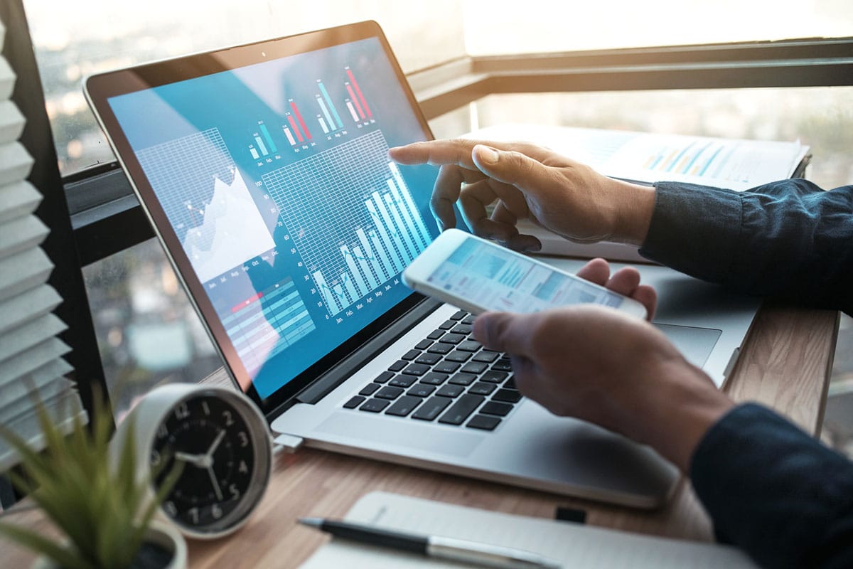 man uses laptop with graphs and figures and cellphone with learning materials in example of future proofing work through training