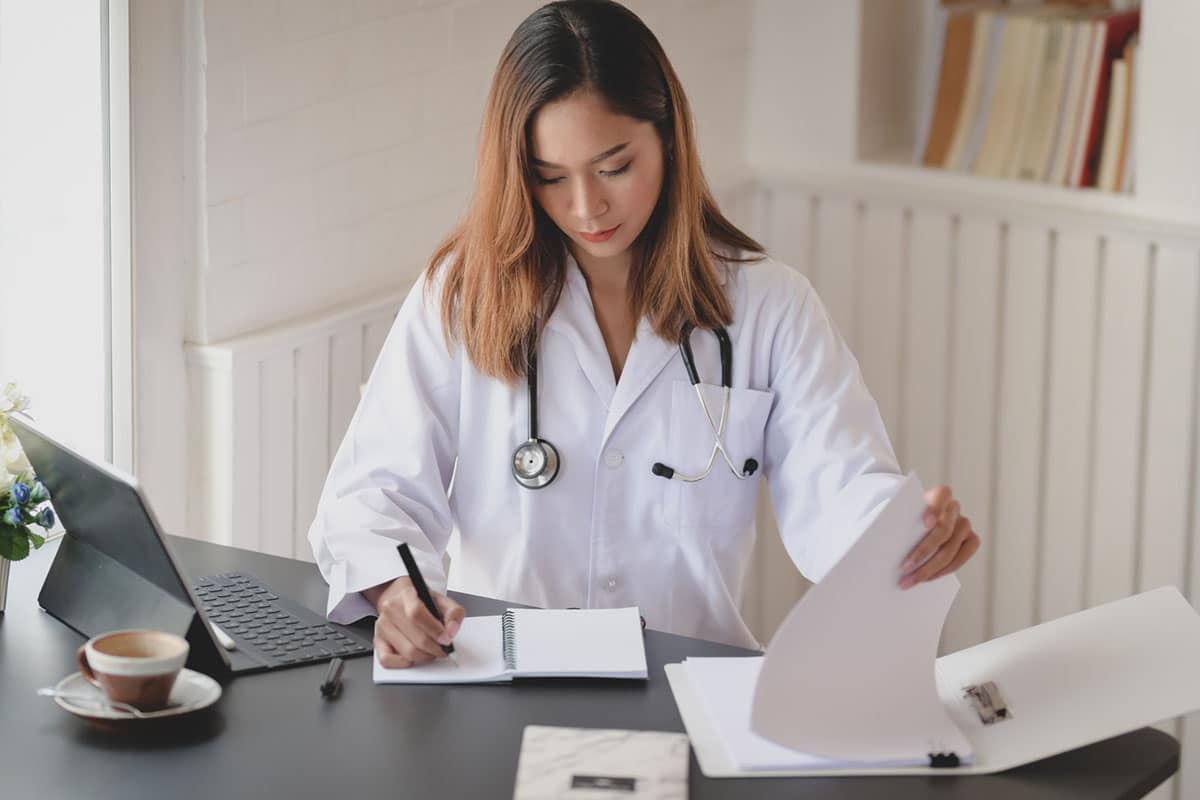 medical woman makes notes while looking over her files