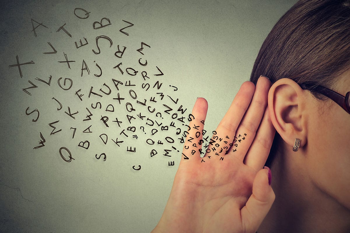 woman holding hand to ear with letters overlaid indicating sensory information