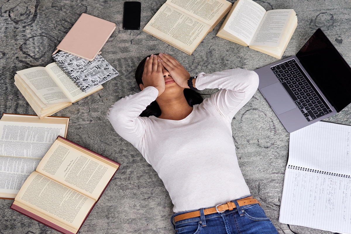 woman lies down covering eyes seems overwhelmed by various information