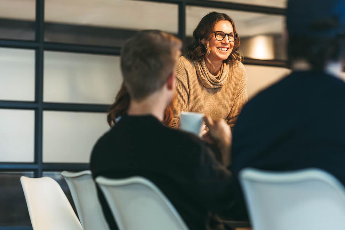 woman stands during meeting leading conversation showing leadership skills