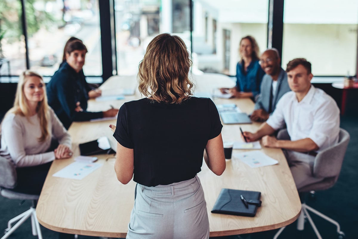 woman stands in front of team demonstrating communication and leadership as key principles of change management