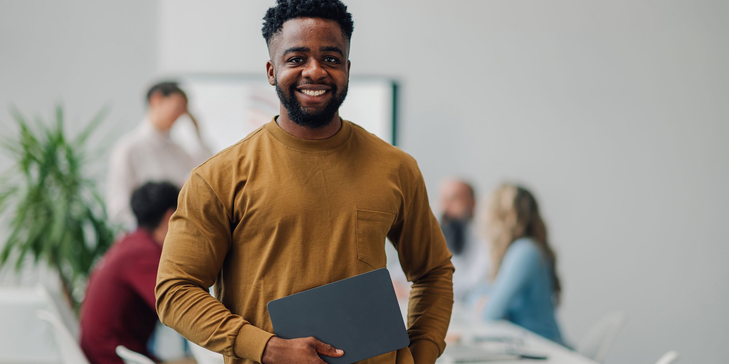 student stands in front of room with others meeting in the background