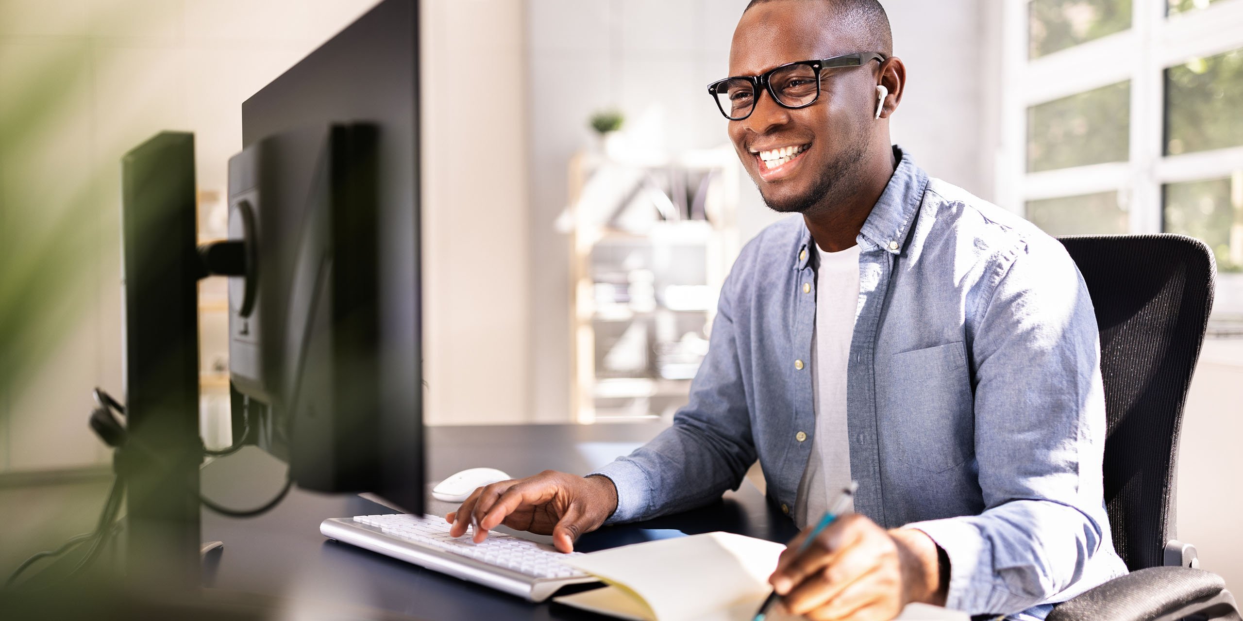 employee smiles while accessing training on desktop and making notes